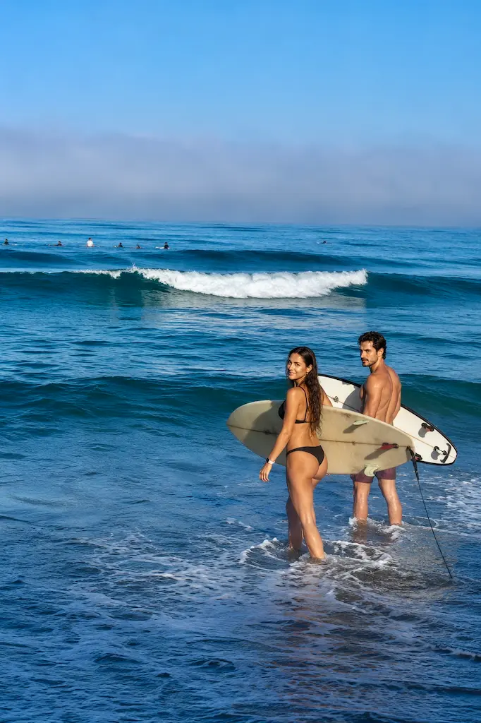 Two surfers going to the ocean holding their surfboards.