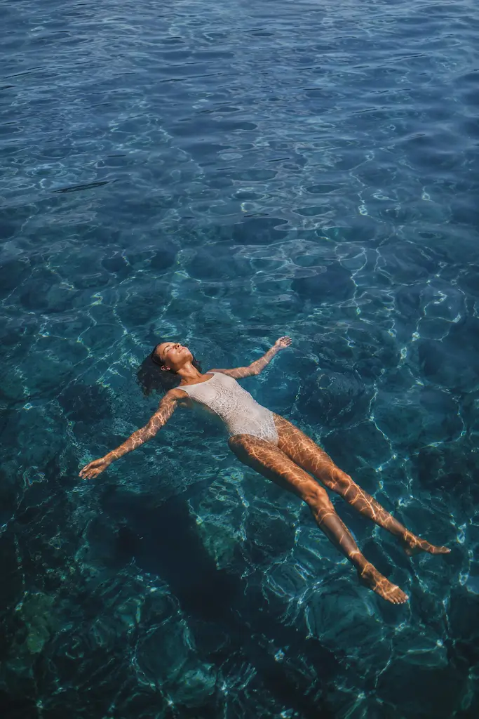 Woman floating peacefully on her back in clear blue water
