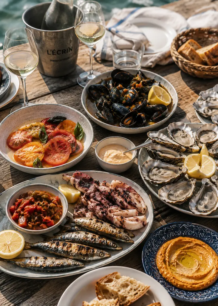Mediterranean seaside lunch with grilled sardines, calamari, mussels, oysters, tomatoes, bread and chilled wine.
