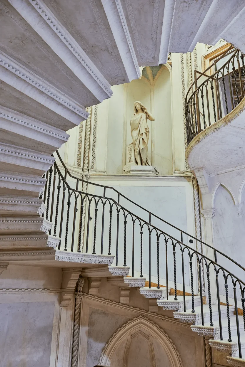 Historic octagonal staircase at Palazzo Donà Giovannelli with stone steps, decorative ironwork and a painted vaulted ceiling.