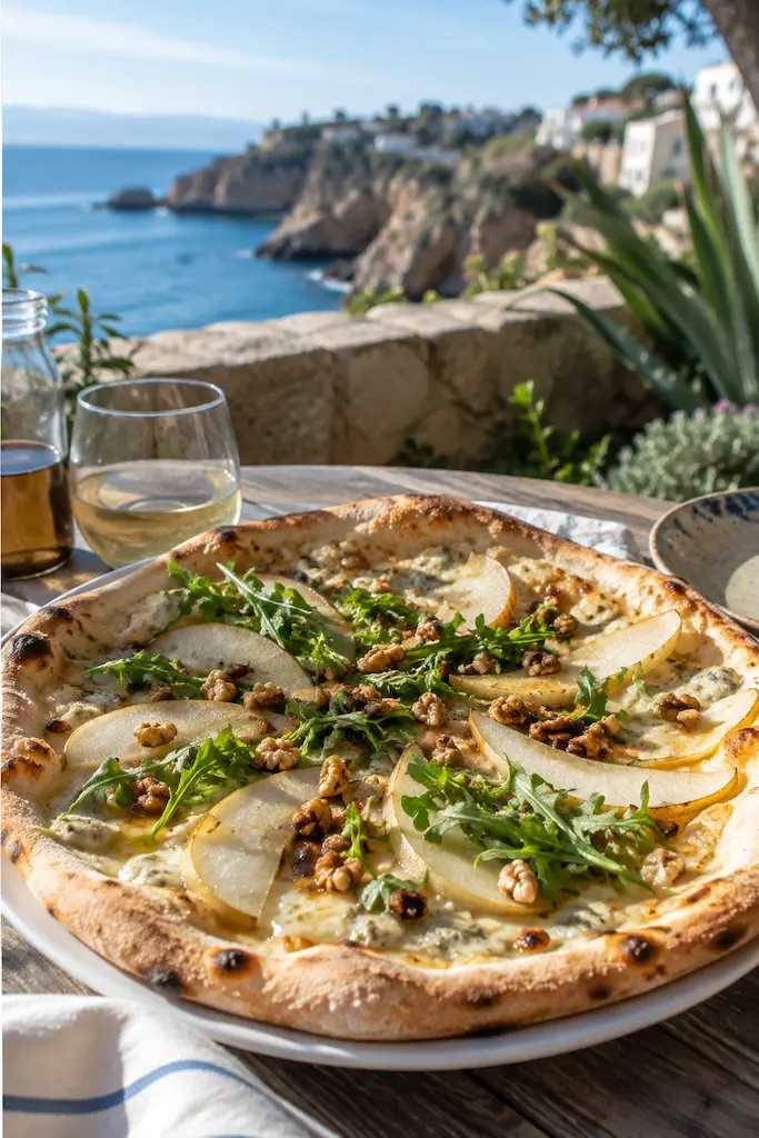 Pear and blue cheese pizza topped with walnuts and arugula on a sunlit table overlooking the California coast.