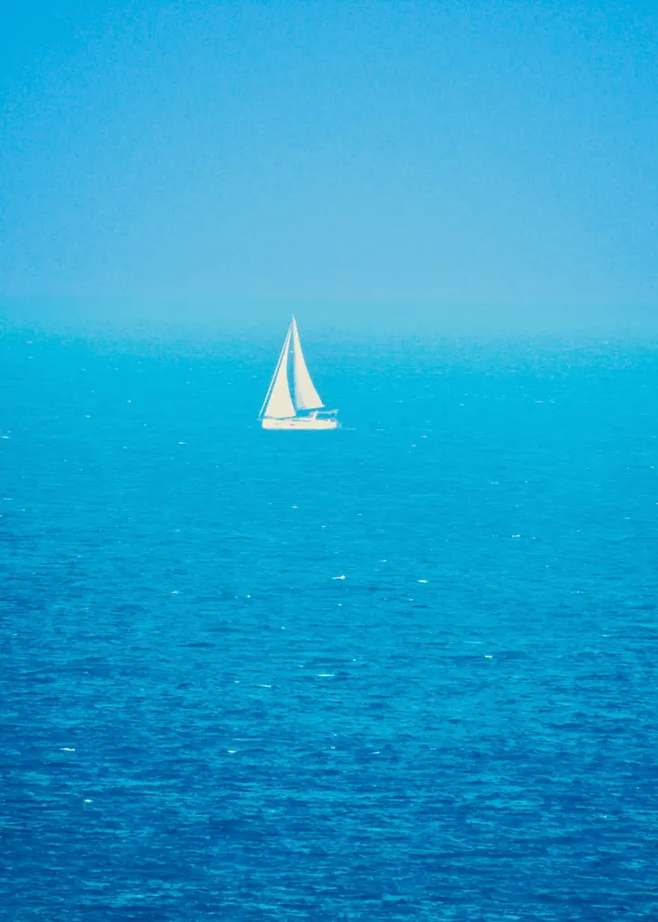 Sailboat crossing bright blue Mediterranean water under full sail