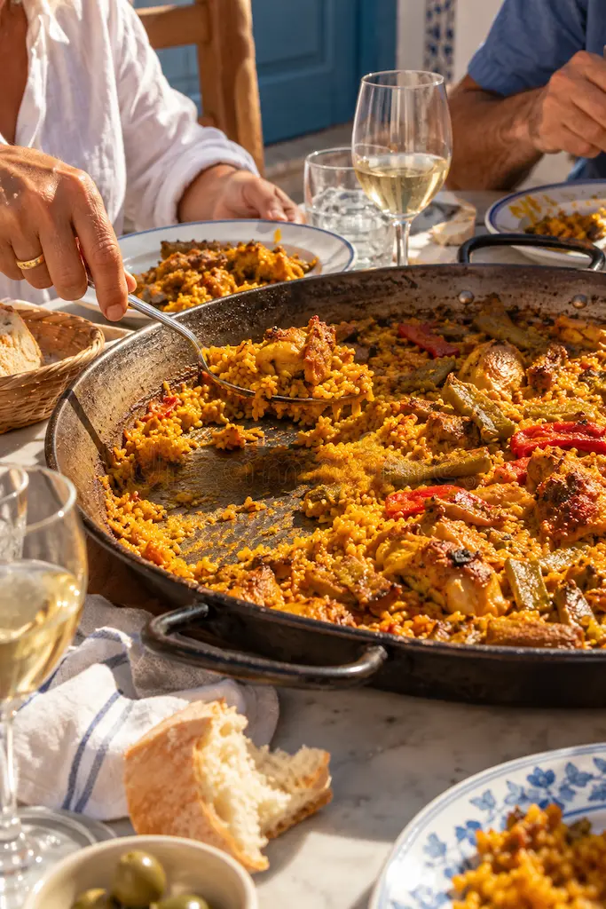Traditional Valencian rice dish served from a large paella pan at a lunch table in Valencia